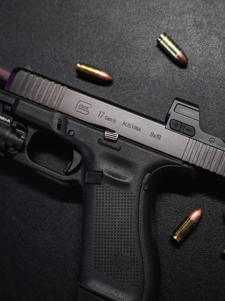 Le Glock 17 Gen5 et son point rouge vus de dessus, avec des cartouches de 9 mm