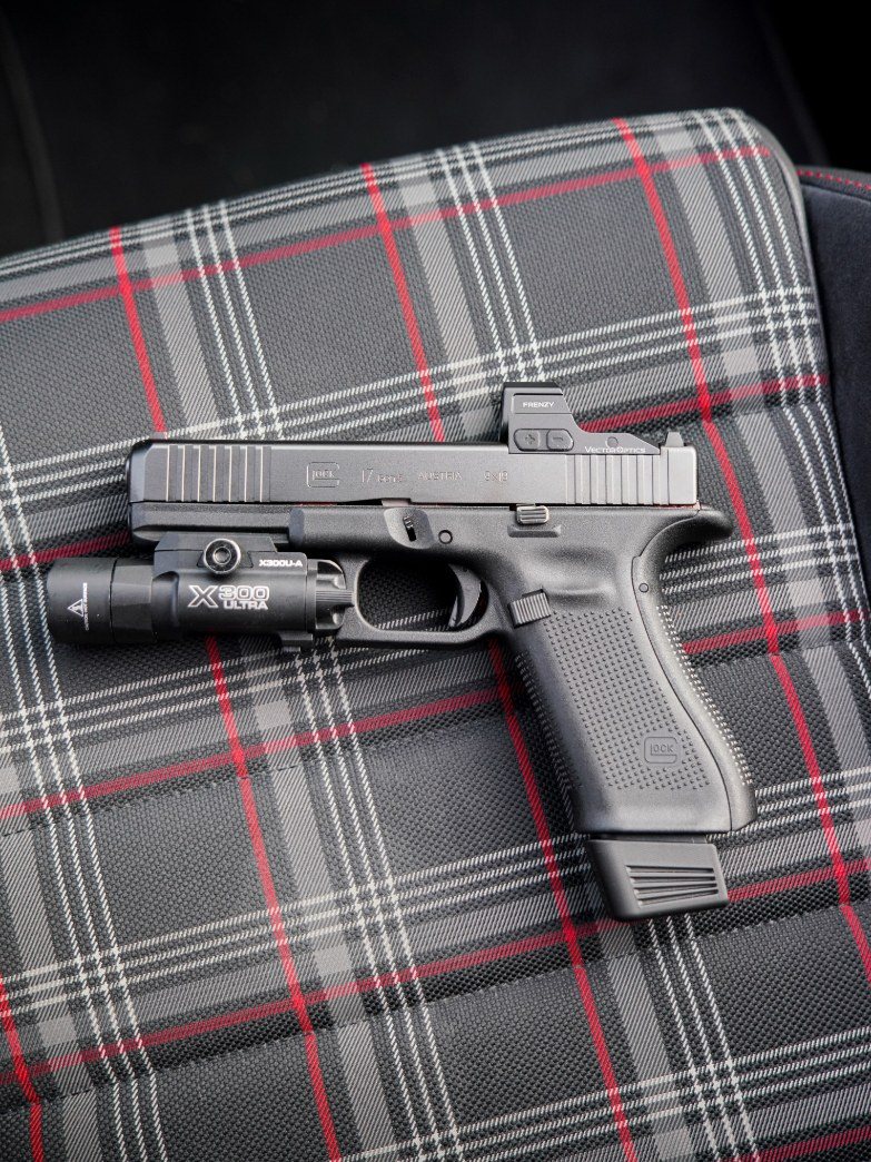 Vue d'ensemble du Glock 17 Gen5 avec sa lampe sur un tissu écossais